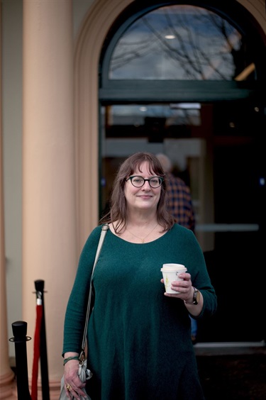 Woman holding a coffee smiling at the front entrance of the newly refurbished BMH