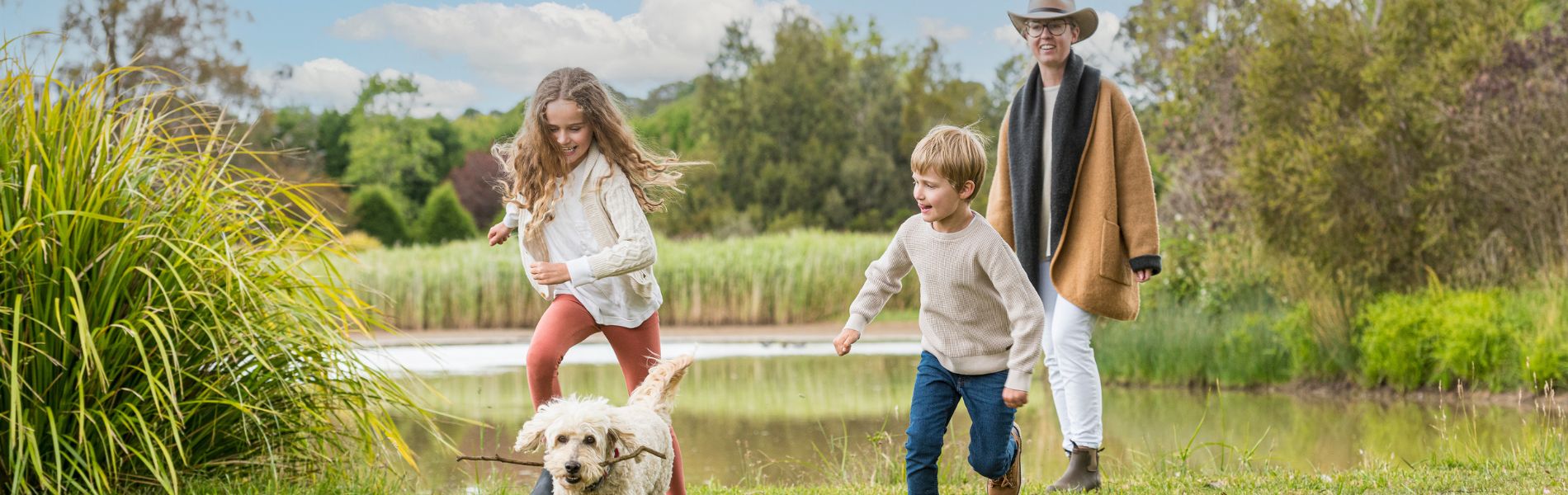 Family running with dog in parkland in Wingecarribee Shire