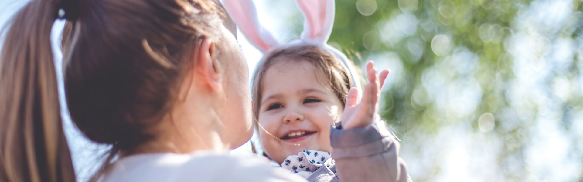 Woman holding a smiling baby wearing fluffy pink Easter bunny ears