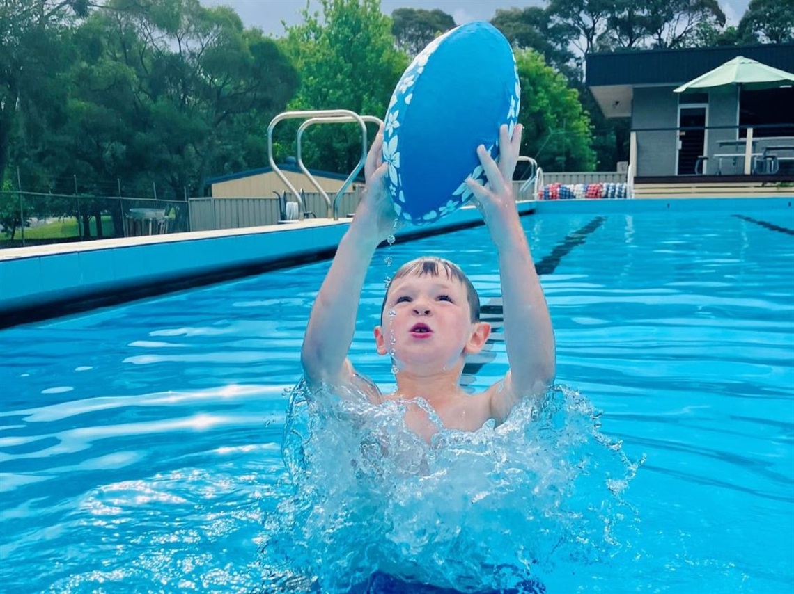 Boy playing in bowral learning pool with a water toy