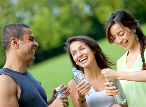 Man and 2 women smiling and happy outside with water bottles 